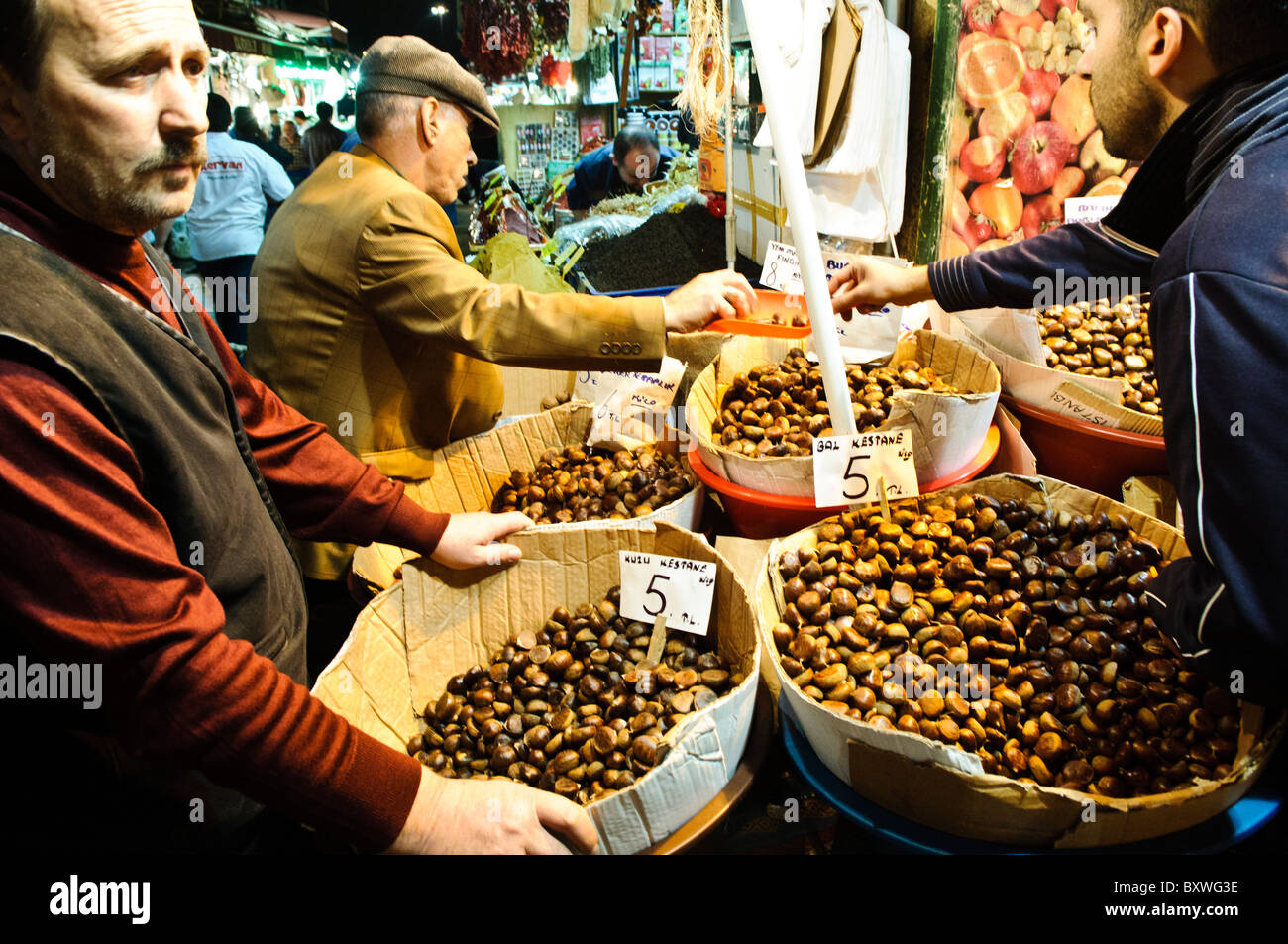 Spice Bazaar Nuts for sale Istanbul Turkey // ISTANBUL, Turkey — i clienti acquistano castagne, pistacchi e altre noci da venditori ambulanti vicino al Spice Bazaar (noto anche come Egyptian Bazaar) a Istanbul. Il Bazaar delle spezie, uno dei più antichi mercati coperti della città, fu costruito nel 1660 come parte del complesso della nuova Moschea. Il mercato era tradizionalmente un importante centro commerciale per spezie, erbe e altri beni provenienti dall'Asia e dall'Egitto. Situato nel quartiere di Eminönü, il bazar continua ad attrarre sia la gente del posto che i turisti alla ricerca di specialità e spezie tradizionali turche. Foto Stock
