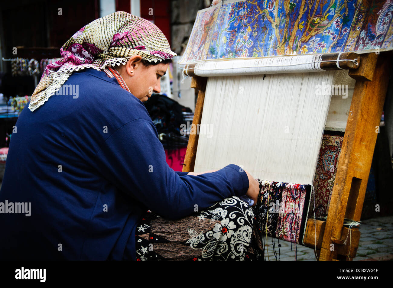 ISTANBUL, Turchia / Türkiye — Una donna usa un telaio per tessere un tappeto turco presso l'Arastar Bazaar, un piccolo bazar vicino alla Sultanahment Camii (Moschea Blu) a Istanbul, Turchia. Foto Stock