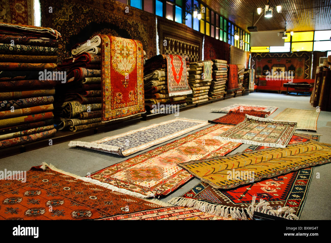 Tappeti turchi presso l'Arasta Bazaar Istanbul // ISTANBUL, Turchia - interno di un negozio di tappeti turchi presso l'Arasta Bazaar, un piccolo mercato coperto situato accanto alla Moschea del Sultano Ahmed (nota anche come Moschea Blu) nel quartiere Sultanahmet di Istanbul. L'Arasta Bazaar, costruito all'inizio del XVII secolo come parte del complesso della Moschea del Sultano Ahmed, è stato originariamente progettato per generare entrate per la manutenzione della moschea attraverso il reddito di affitto dai suoi negozi. Il bazar è specializzato in artigianato turco tradizionale, tessuti e tappeti, servendo sia i turisti che la gente del posto. La Moschea del Sultano Ahmed Foto Stock