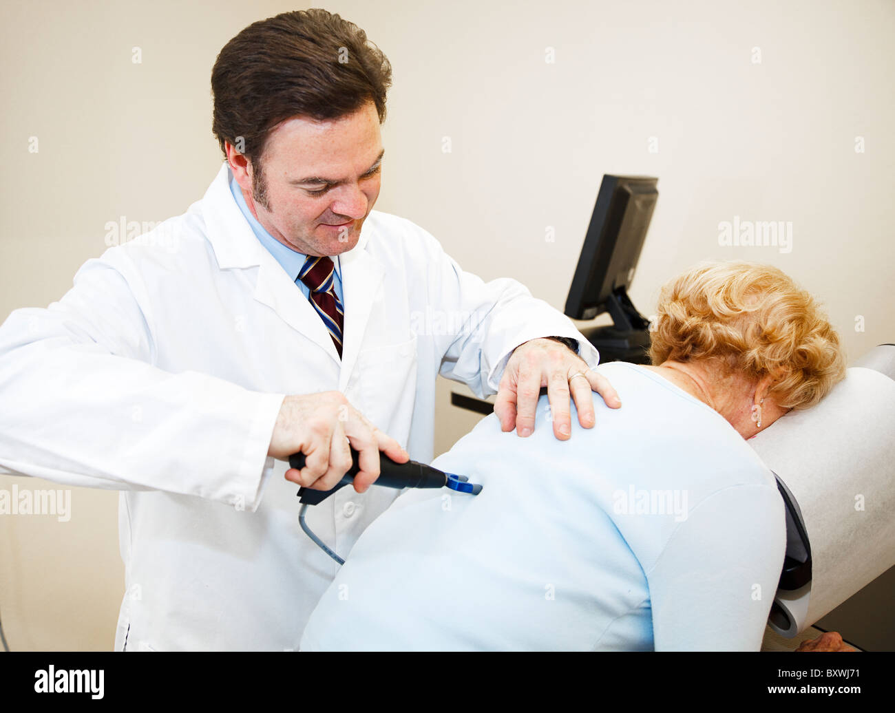 Chiropratico utilizza la più recente tecnologia del computer per la diagnosi e il trattamento di un paziente. Foto Stock