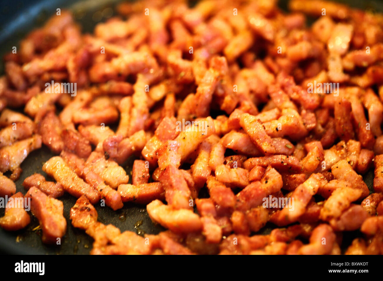 Strisce di pancetta friggere in una padella. Foto Stock