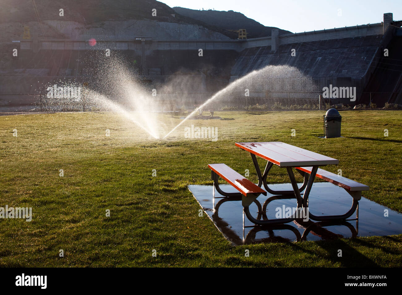 Stati Uniti d'America, Washington, il sole di mattina delle luci di sprinkler acqua e area picnic nella parte anteriore del Grand Coulee diga sul fiume Columbia di sunrise Foto Stock