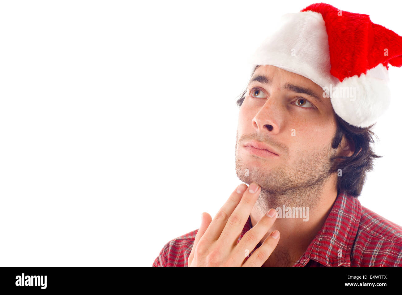 Uomo sorridente con il Natale Red Hat guarda pensieroso -isolate su uno sfondo bianco Foto Stock