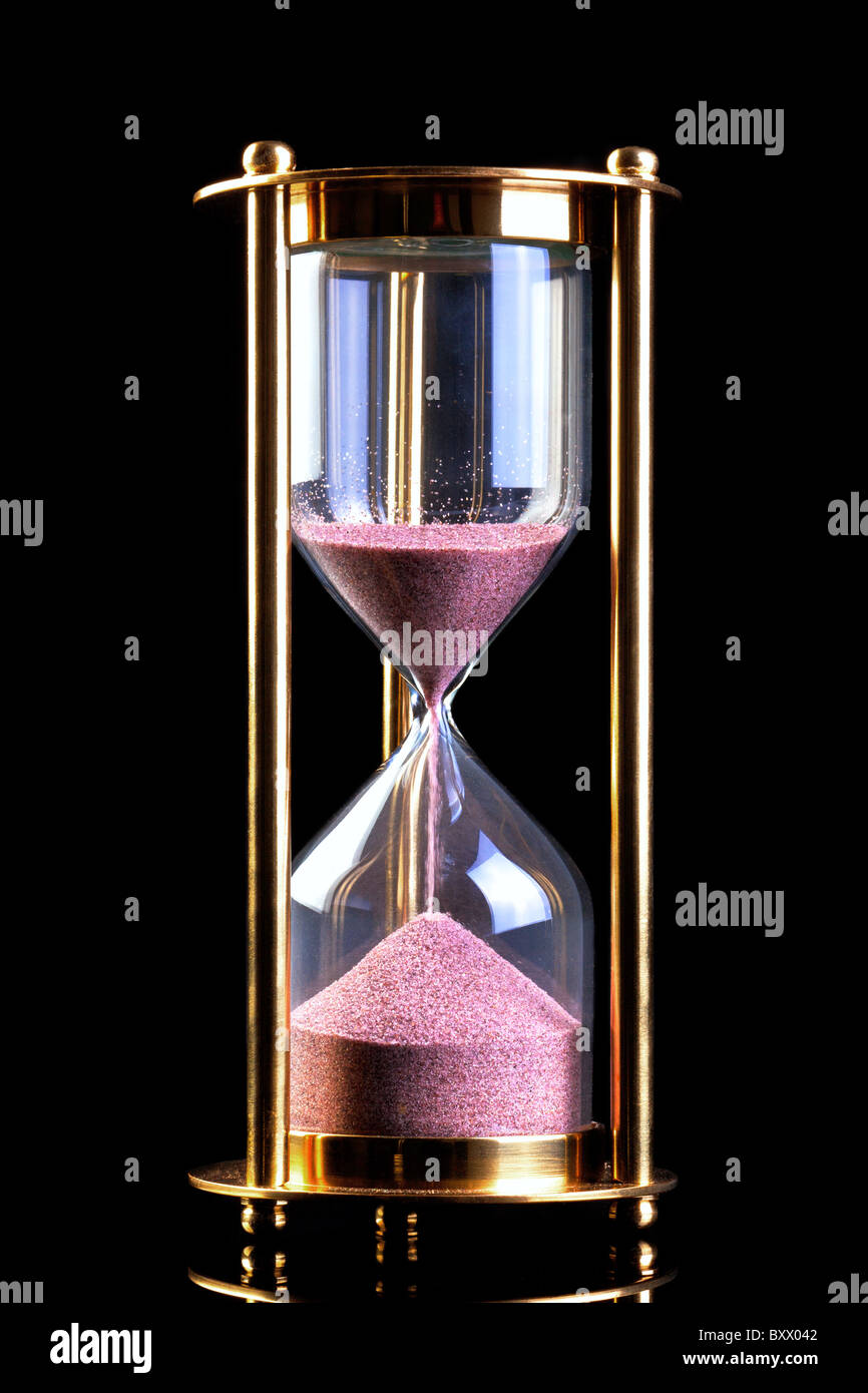 Una clessidra in ottone o timer di sabbia isolata su uno sfondo nero. Foto Stock