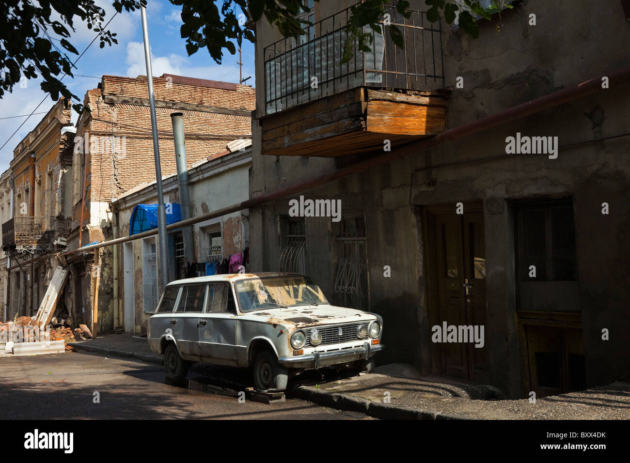 Vecchia auto in strada con il collasso fatiscente e balconied vecchi edifici di Tbilisi città vecchia, Kala, Georgia. JMH4002 Foto Stock