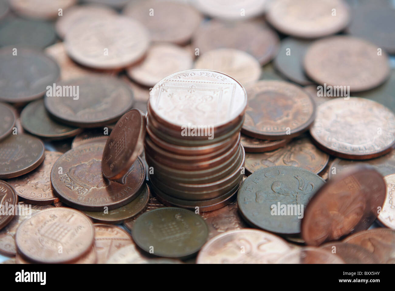 Una sterlina 1p coin appoggiata contro una pila di 2p delle monete in euro - tutti in piedi su una ridda di 2p e 1p delle monete in euro Foto Stock
