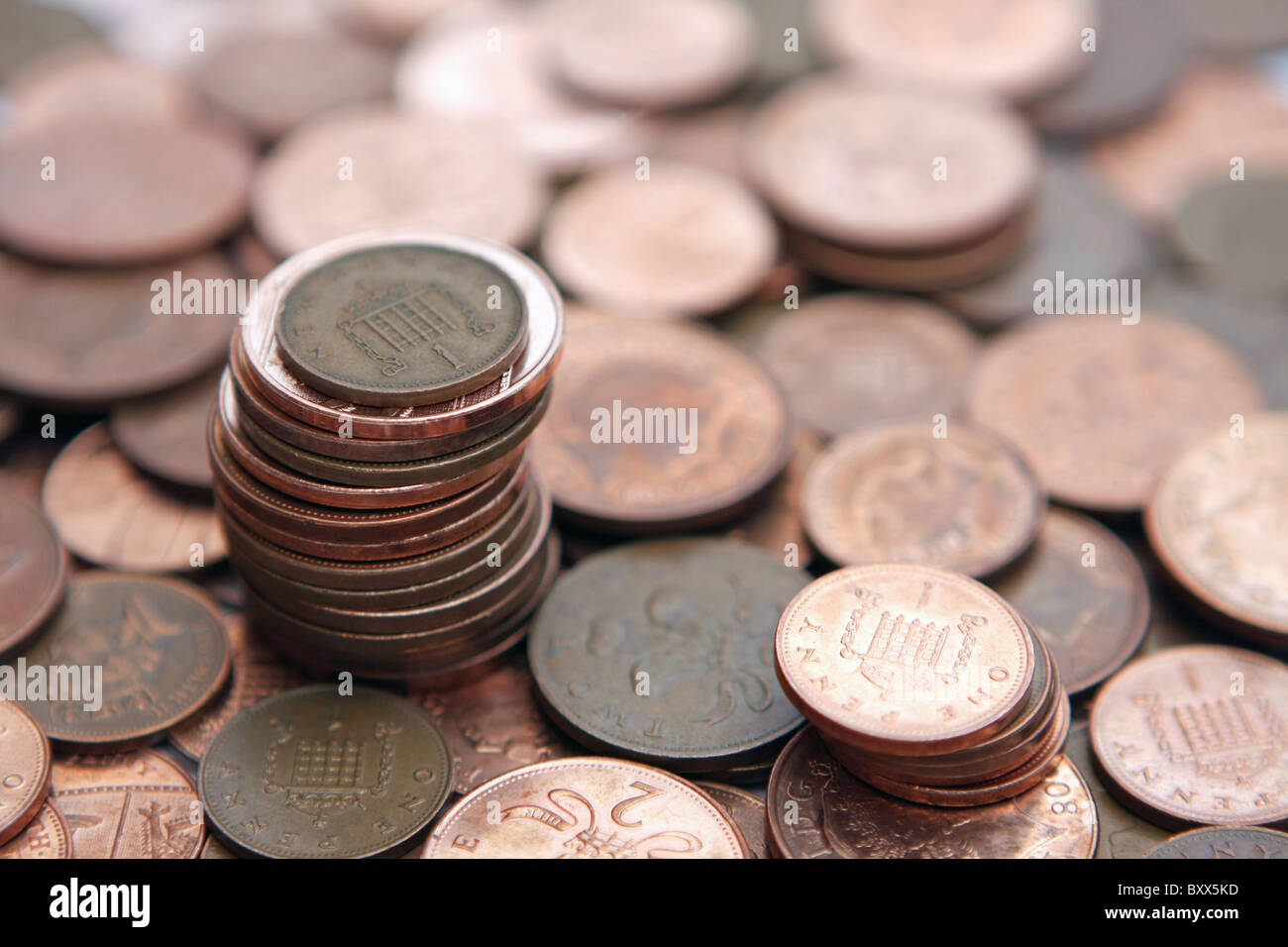 Una sterlina 1p moneta su una pila di 2p monete e una piccola pila di 1p delle monete in euro - tutti in piedi su una ridda di 2p e 1p delle monete in euro Foto Stock