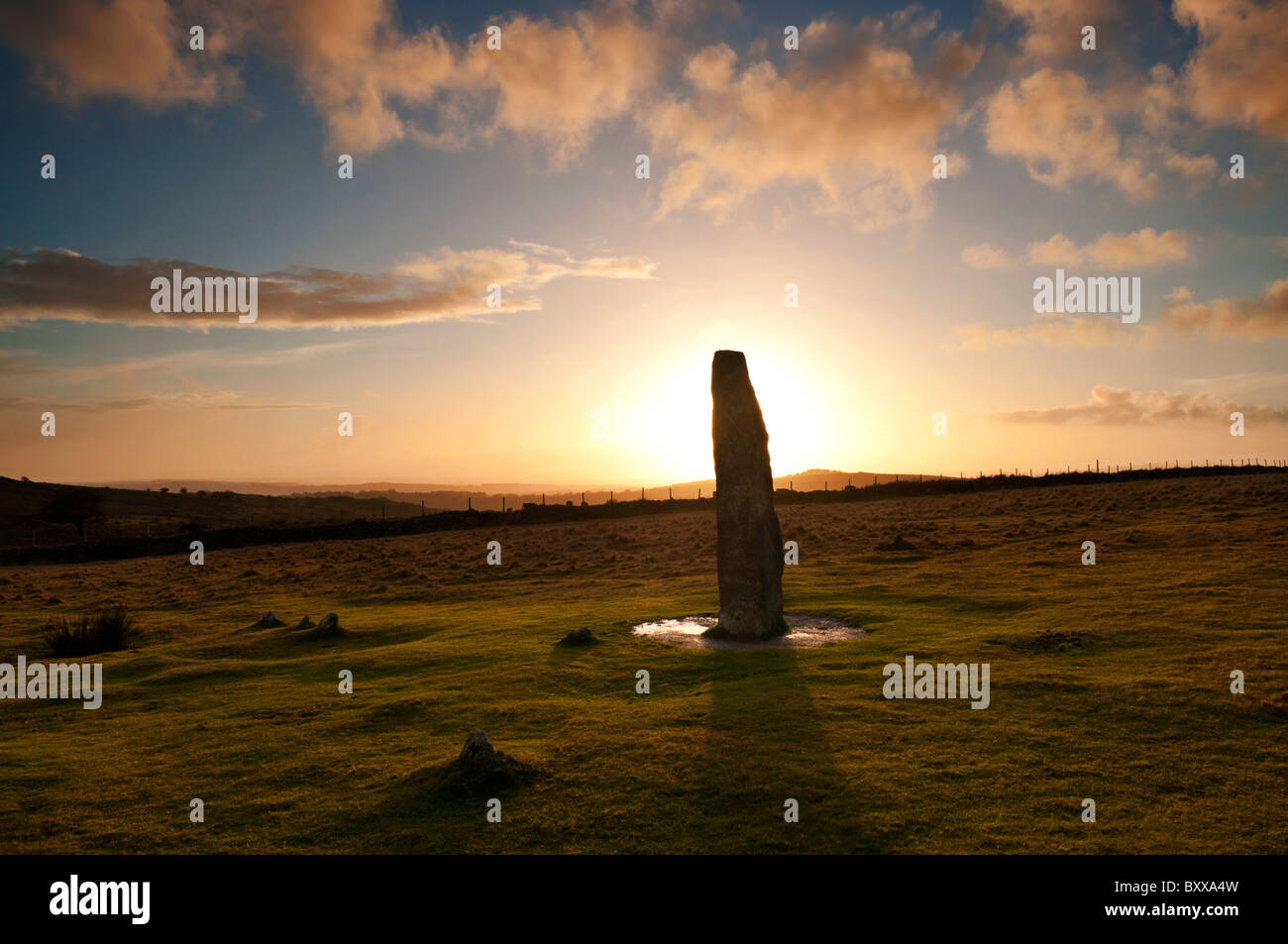 Pietra permanente stagliano contro il sole di setting a Merrivale, Dartmoor Devon UK Foto Stock