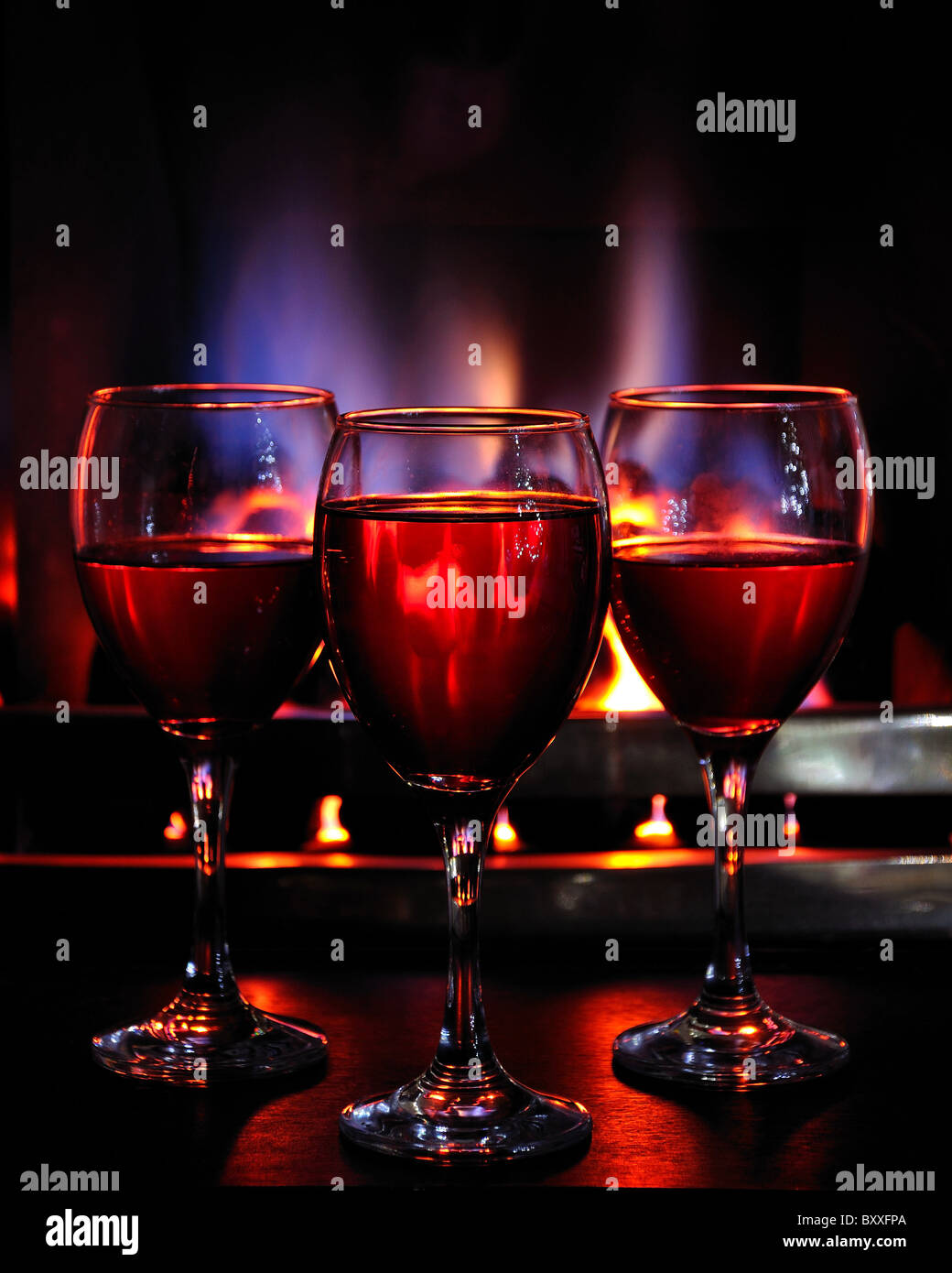 Bicchieri di vino davanti ad un fuoco di fiamma di vino rosso di succo di mirtillo palustre fuoco caldo tepore invernale toast celebrare la festa del nuovo anno festive Foto Stock