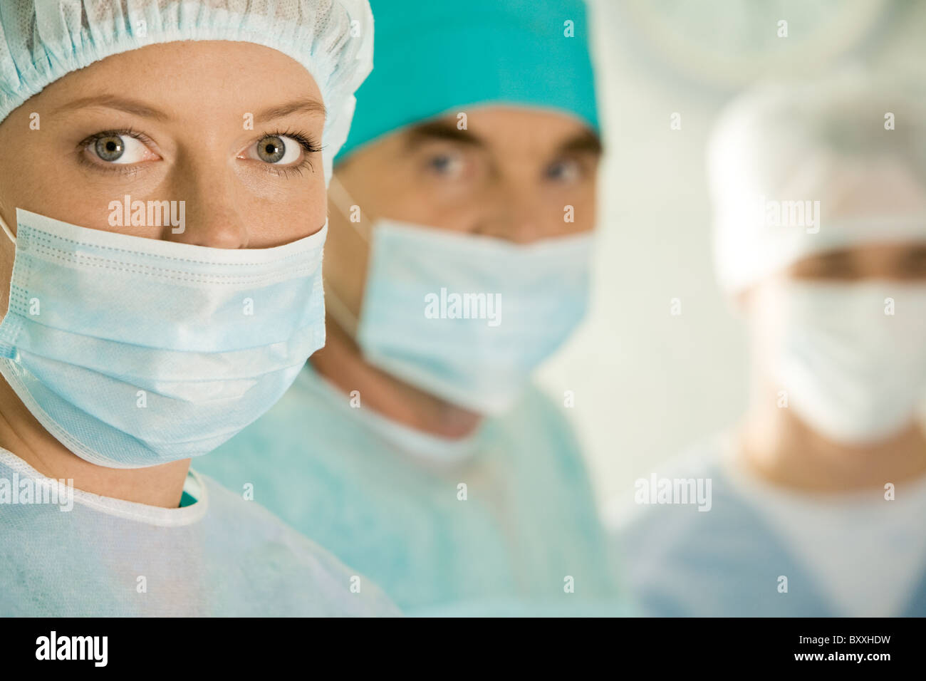 Ritratto di donna chirurgo di indossare la maschera protettiva sullo sfondo dei suoi colleghi Foto Stock