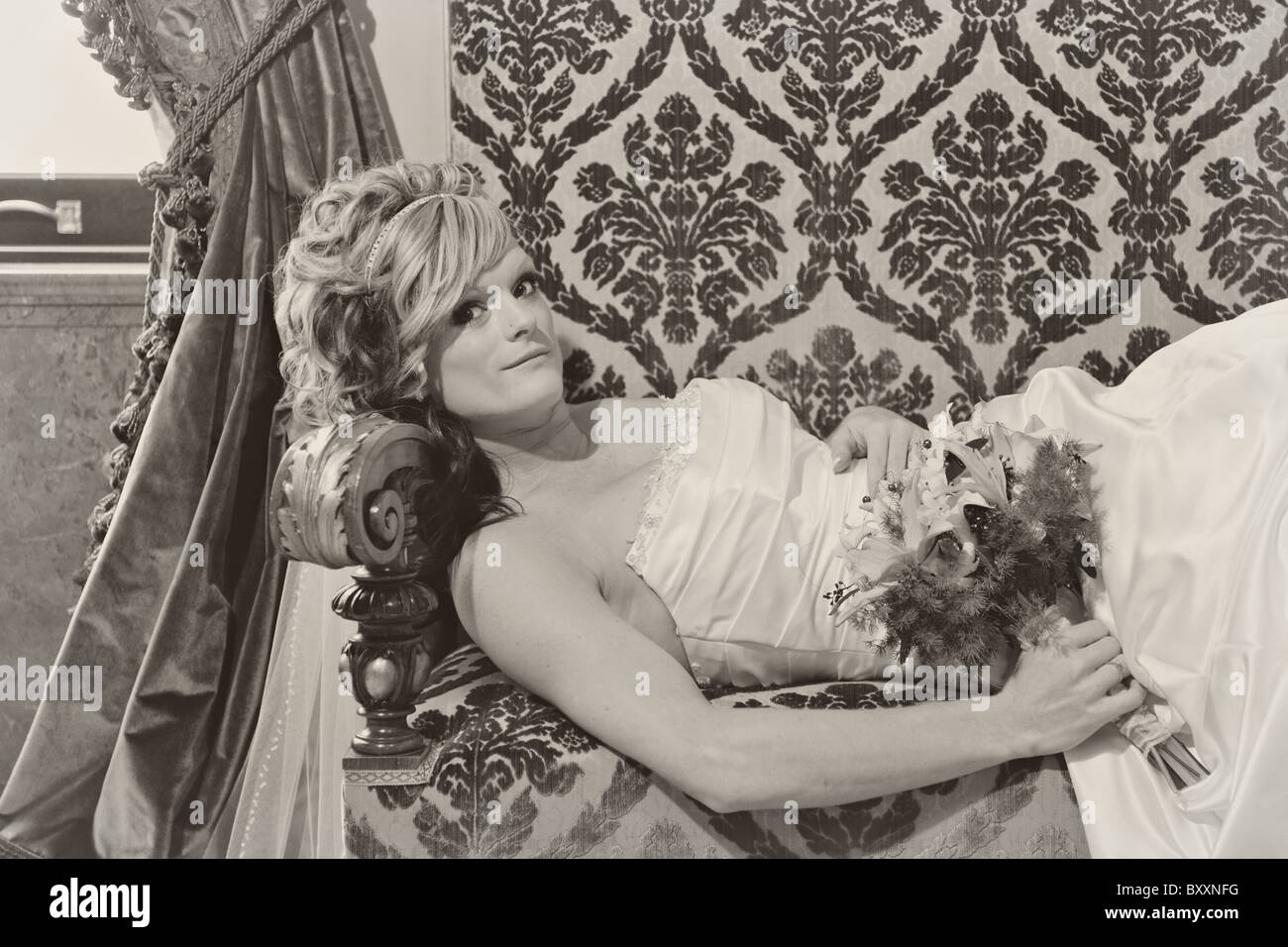 Il nero di seppia monocroma sposa sdraiato sul lettino di damasco a metà lunghezza Foto Stock