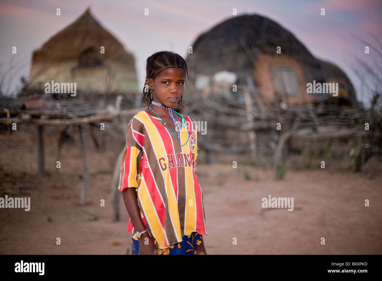 In Fulani remoto villaggio di Pete Goonga nel nord del Burkina Faso, una ragazza Fulani si erge di fronte due miglio graineries. Foto Stock