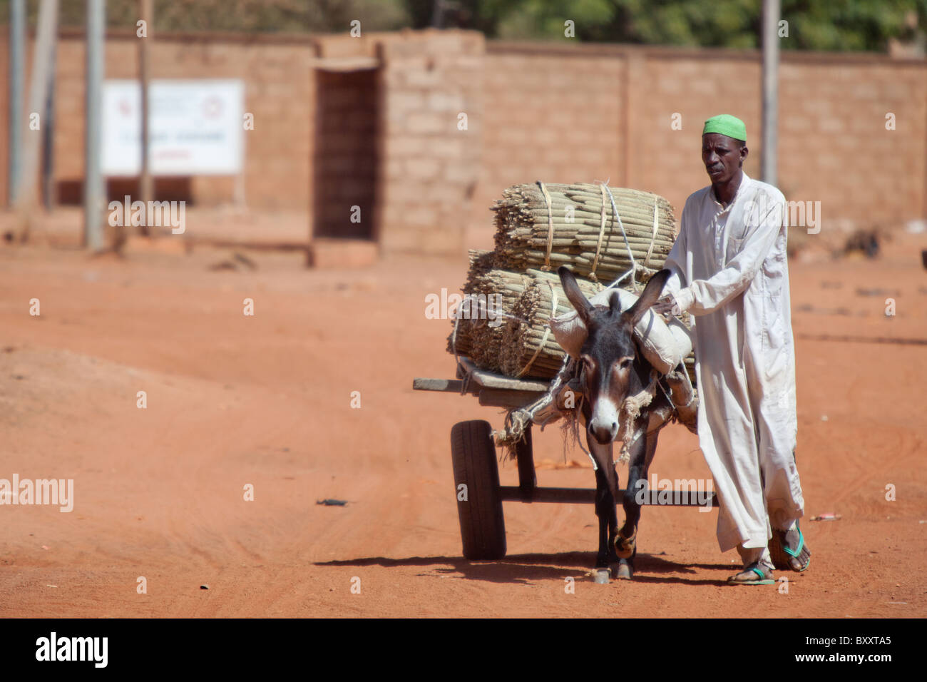 Nella città di Djibo nel nord del Burkina Faso, un uomo capi a casa con una scorta di miglio. Foto Stock