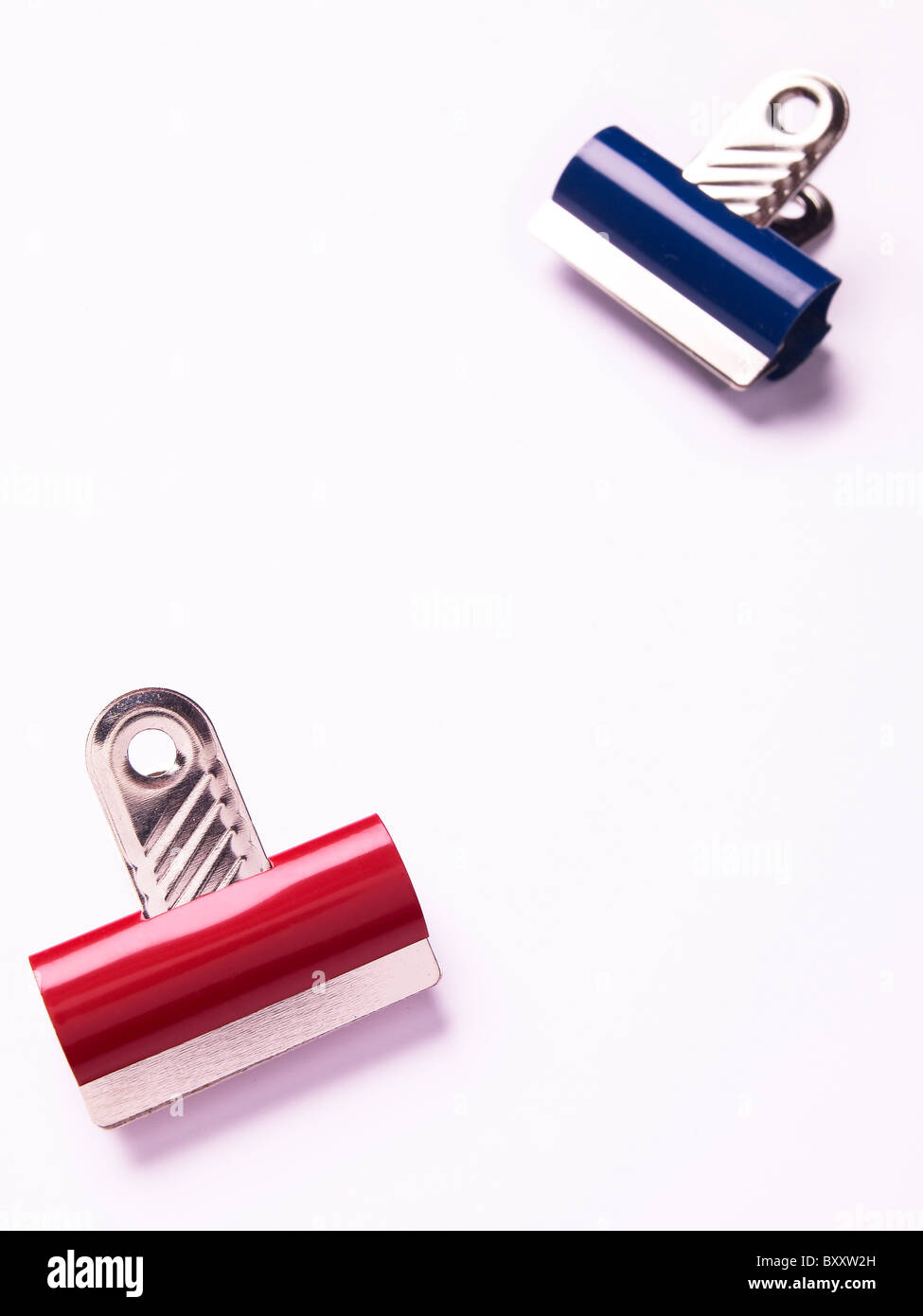 2 due red bulldog clip su uno sfondo bianco blu Foto Stock