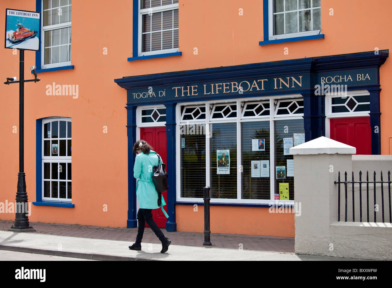 Giovane donna balade passato la scialuppa di salvataggio Inn bar tradizionale in Courtmacsherry, West Cork, Irlanda Foto Stock