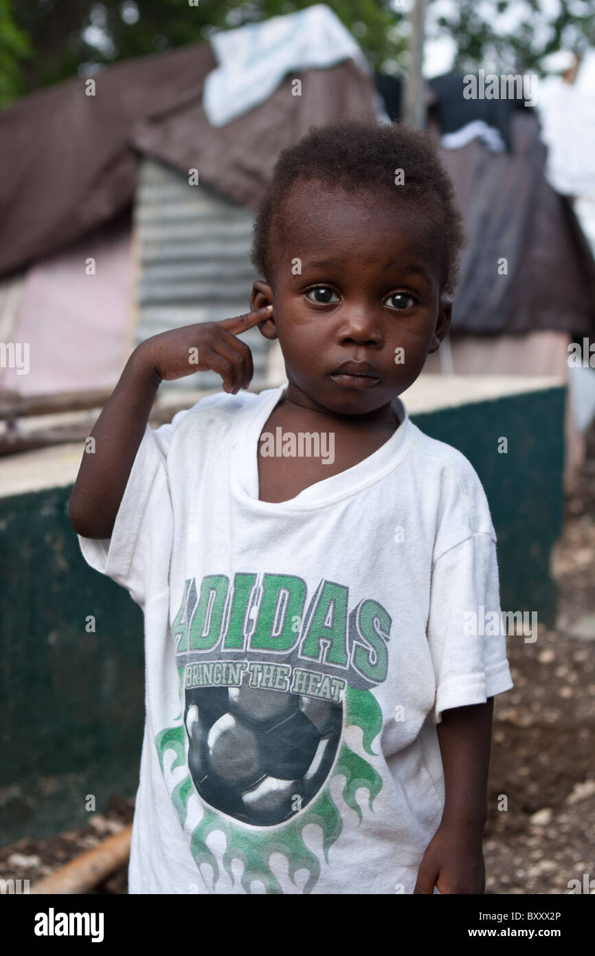 Un giovane ragazzo sta in un campo per sfollati interni di Haiti dopo il terremoto ha distrutto migliaia di case. Foto Stock