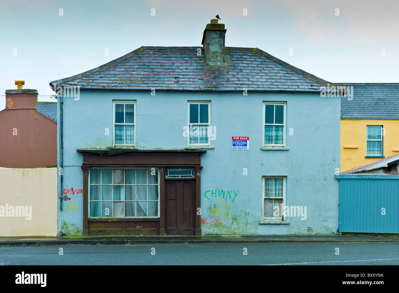 Graffiti su casa con negozio di fronte per la vendita a Kilkee, County Clare, Irlanda Foto Stock