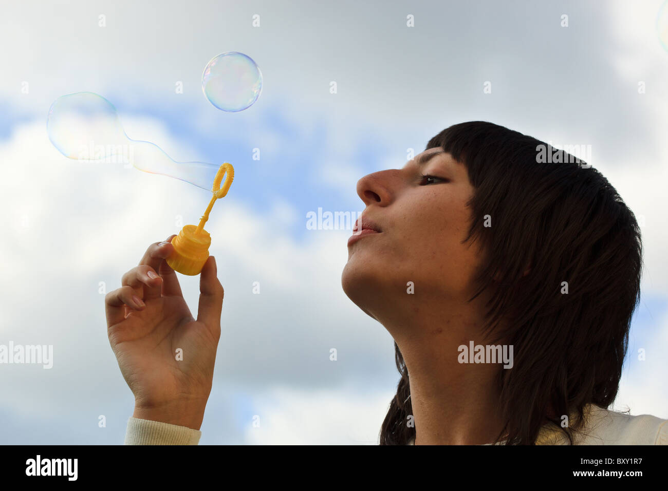 La ragazza si avvia bolle di sapone contro il cielo con le nuvole. Foto Stock