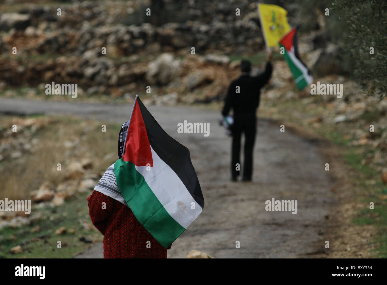 La donna palestinese cammina con la bandiera palestinese durante un rally settimanale contro la costruzione delle barriere di separazione controverse che Israele sta costruendo nel villaggio della Cisgiordania di Bil'in Israele Foto Stock