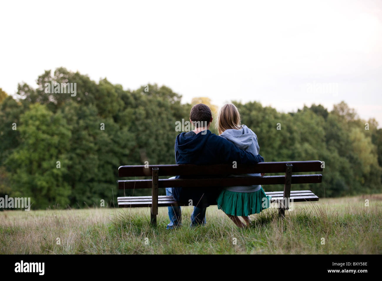 Vista posteriore di una giovane coppia in una panchina nel parco Foto Stock