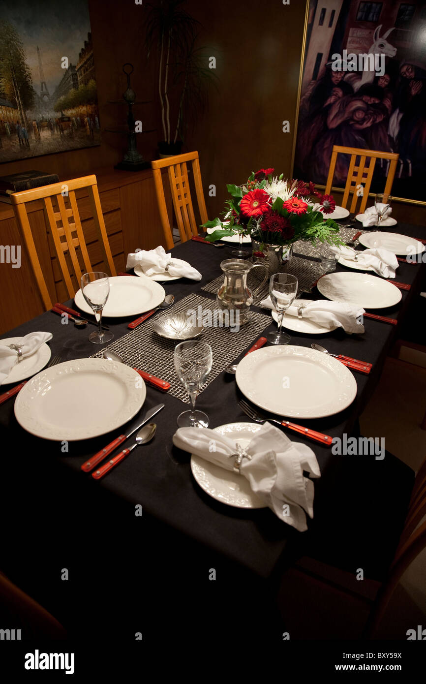 Impostazione tabella su una tovaglia nera con una composizione floreale e  le immagini sulla parete della sala da pranzo Foto stock - Alamy