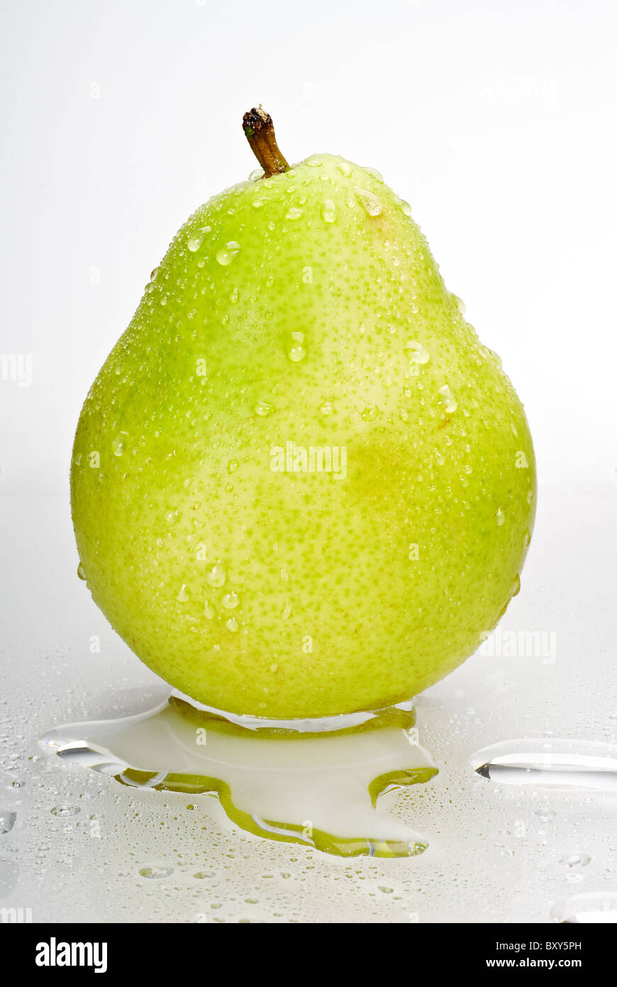 Verde bagnato pera isolato su sfondo bianco con pozza d'acqua Foto Stock