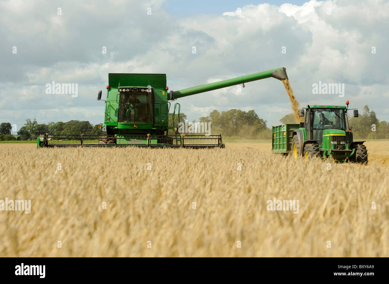 Una mietitrebbia John Deere Harvester la raccolta di orzo in un campo a Holme Gate Farm vicino a Warwick su Eden Foto Stock
