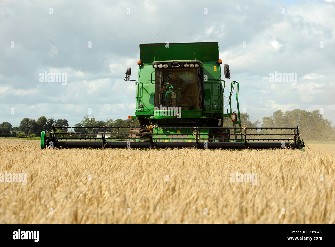 Una mietitrebbia John Deere Harvester la raccolta di orzo in un campo a Holme Gate Farm vicino a Warwick su Eden Foto Stock