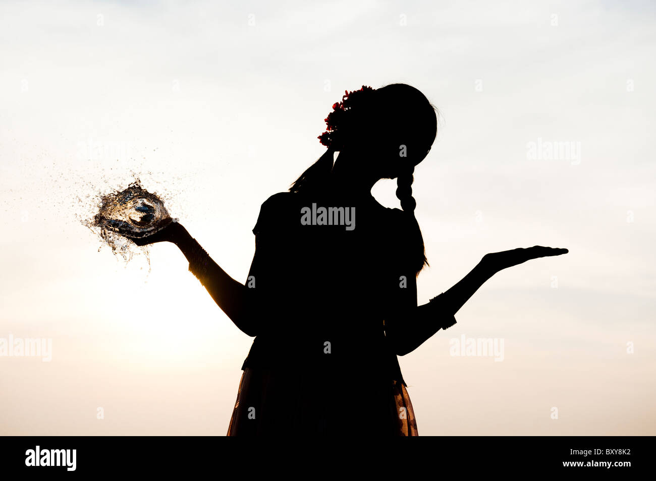 Ragazza indiana tenendo in mano un round burst palloncino dell'acqua. Silhouette . India Foto Stock