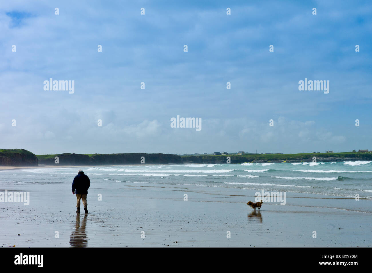 Un uomo e il suo cane, Sheltie cross Corgi, passeggiare sulla spiaggia a Spanish Point, County Clare, costa Ovest dell Irlanda Foto Stock