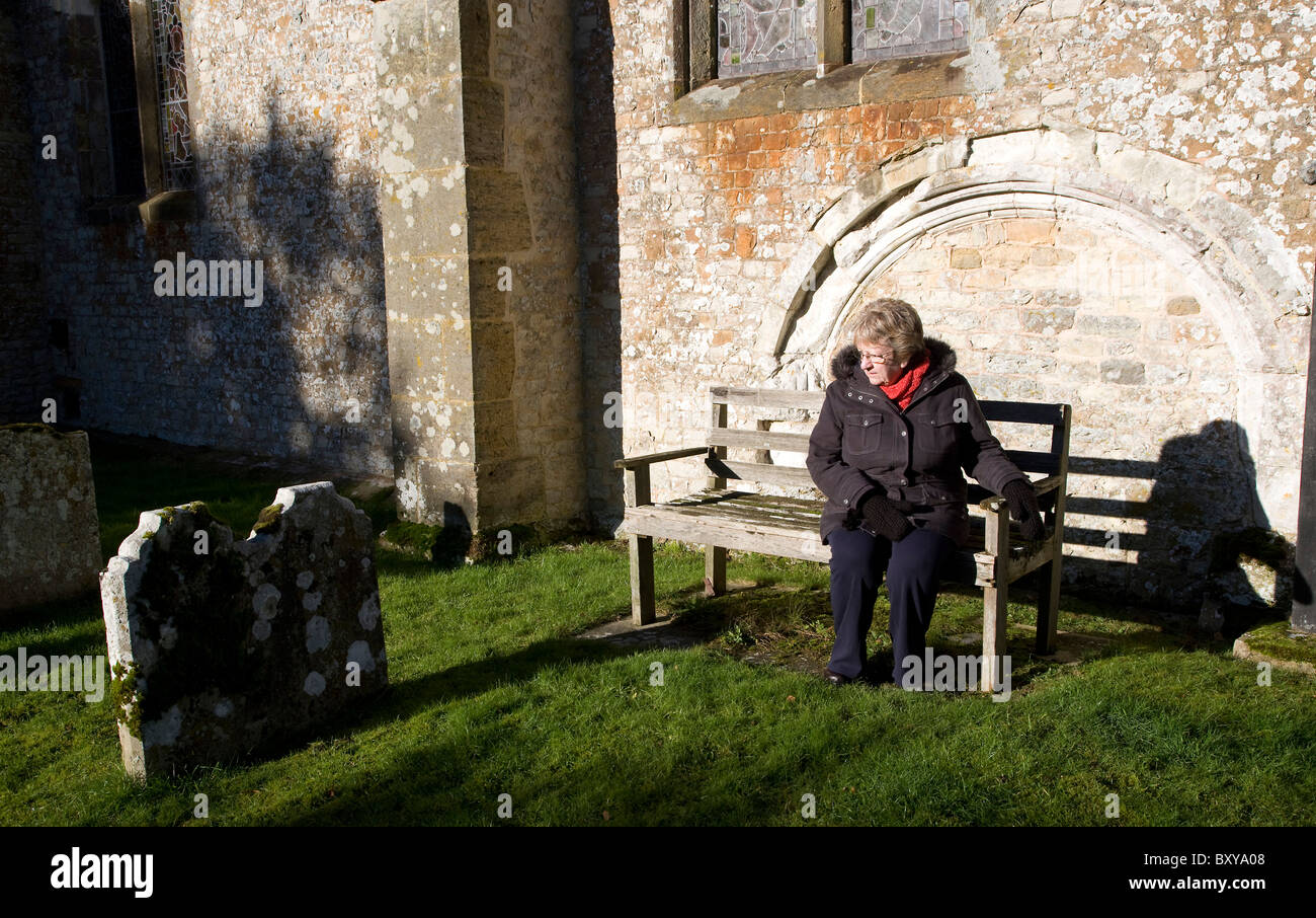 Una signora seduta in un cimitero Foto Stock
