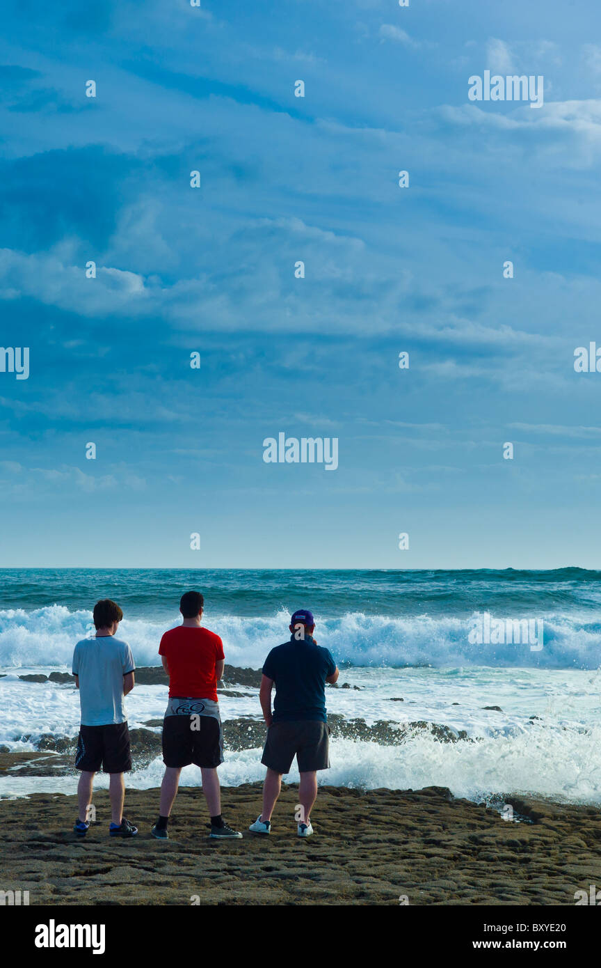 Giovani uomini che guarda al mare guardando le onde che si infrangono, Doolin, County Clare, costa Ovest dell Irlanda Foto Stock