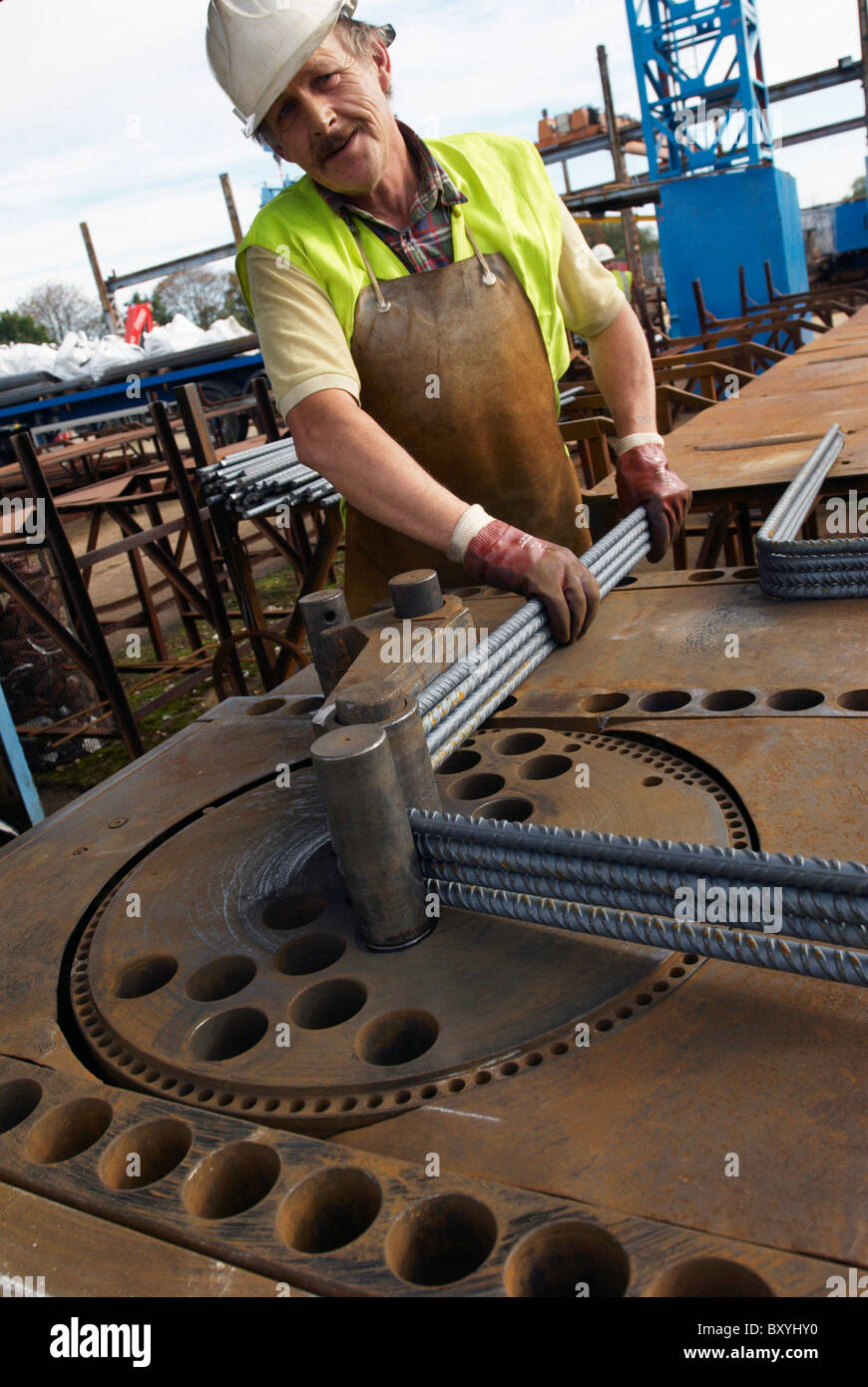 Il rinforzo del cemento armato: tondino di acciaio tagliati e piegati in fabbrica. Lavoratore piegatura di tondini di acciaio Foto Stock