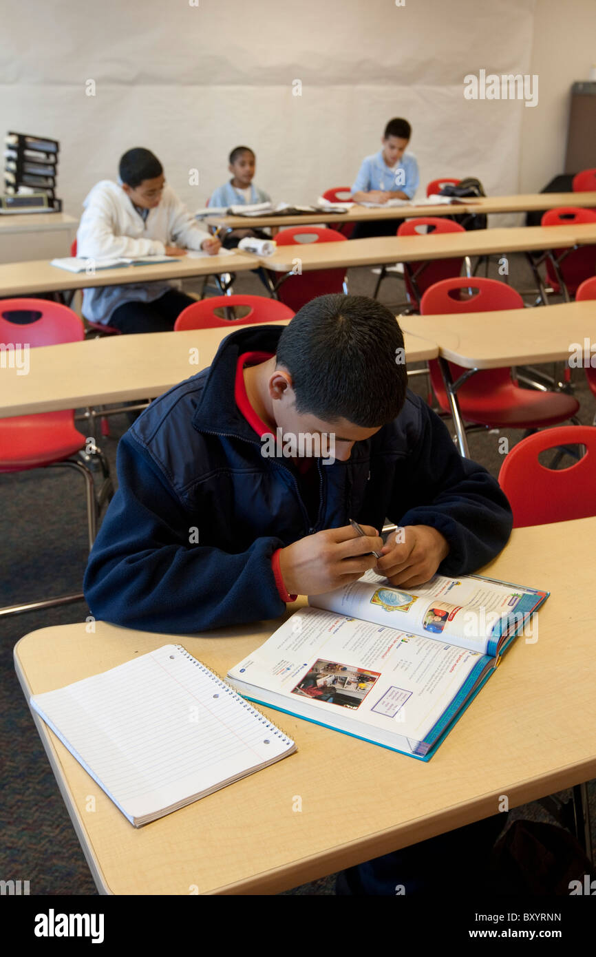 Ispanico studente maschio studi il suo libro di testo in aula a picco Accademia preparatoria carta pubblica di alta scuola in Dallas TX Foto Stock