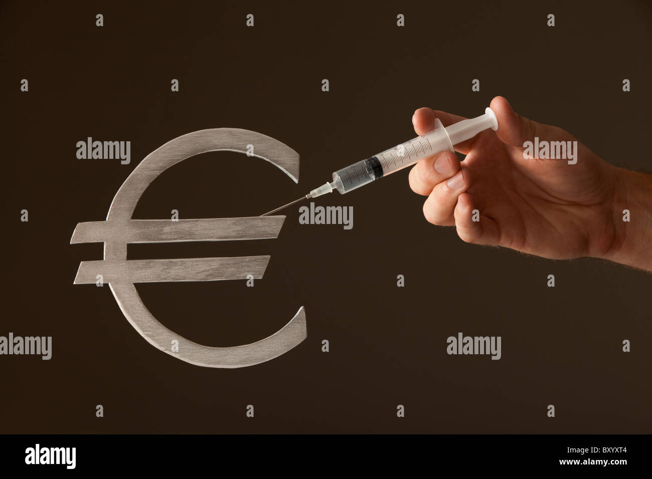 Mano che tiene la siringa sul 'Euro' firmare Foto Stock