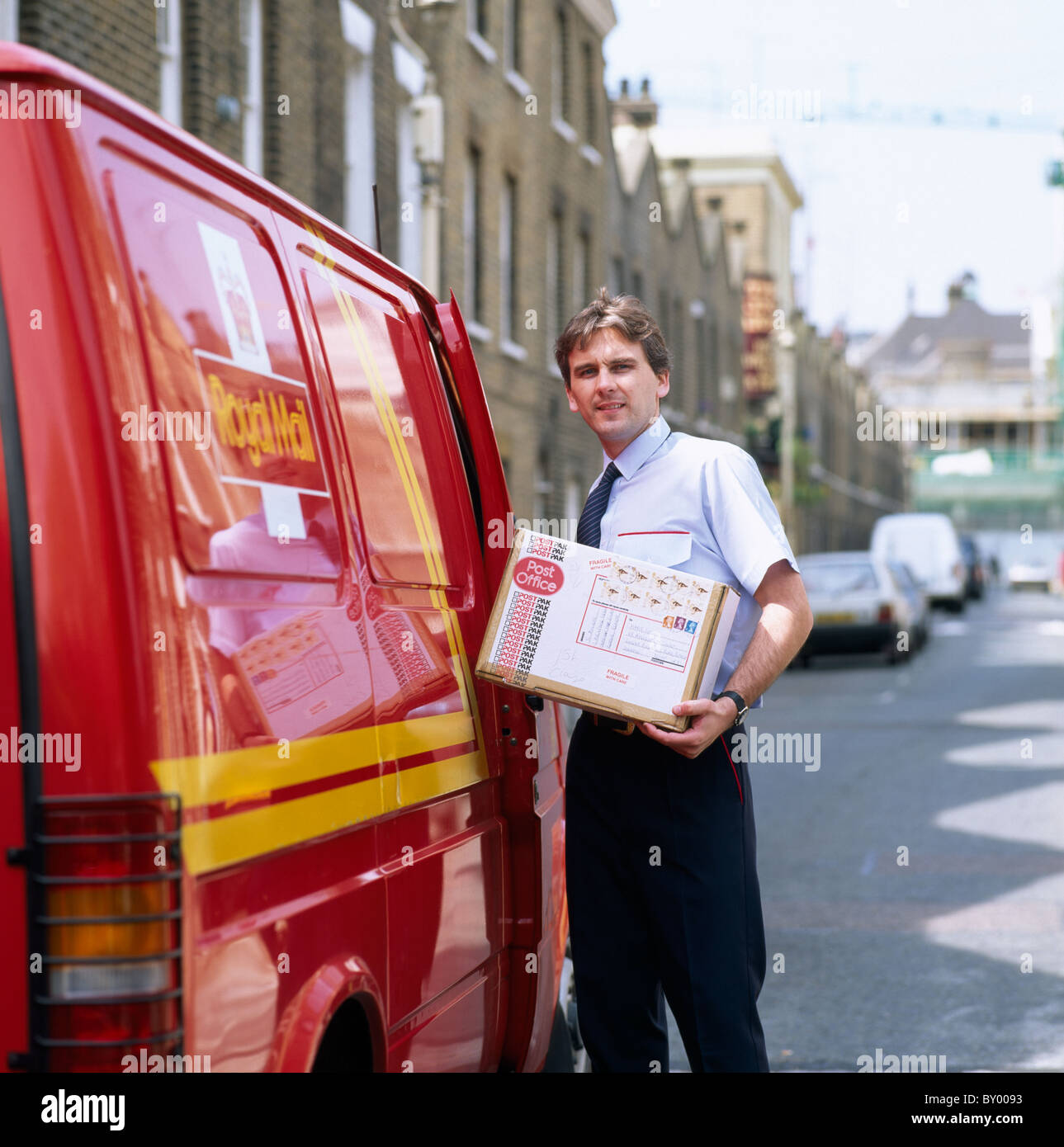 Royal Mail portalettere con un pacchetto a Londra in Inghilterra in Gran Bretagna nel Regno Unito. Occupazione di lavoro Comunicazione di affrancatura postale Foto Stock