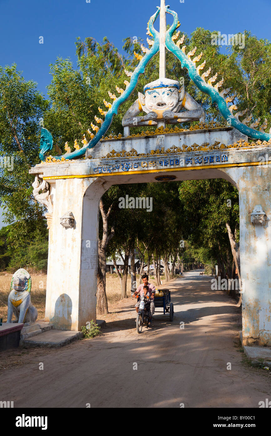 Decorate archway e agricoltore in sella a una moto remorque - provincia di Kandal, Cambogia Foto Stock