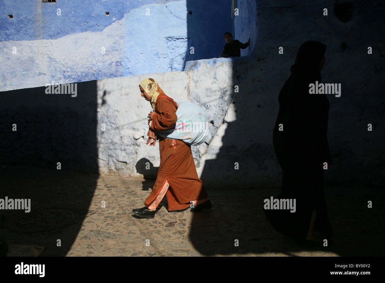 La popolazione locale a piedi intorno al luminoso strade di chefchaouen il luminoso marocco villaggio nelle montagne di riff Foto Stock