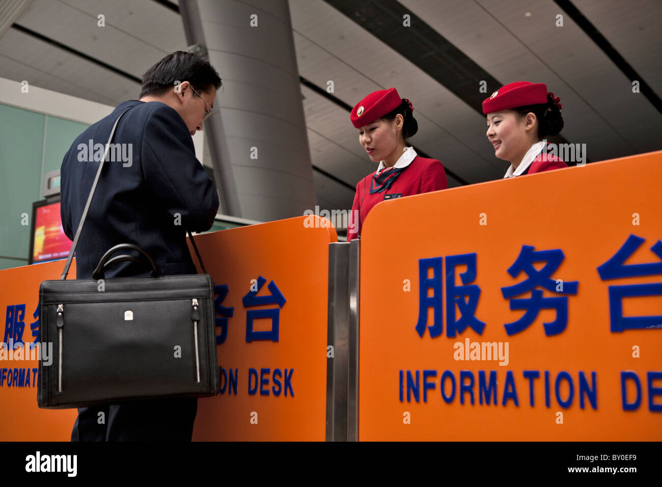 Due hostess un passeggero in Pechino Stazione Ferroviaria Sud, Cina Foto Stock