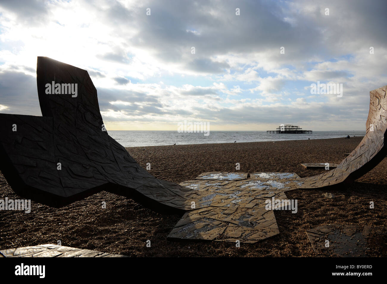 Scultura su Brighton fronte mare con resti di Molo Ovest in background Foto Stock