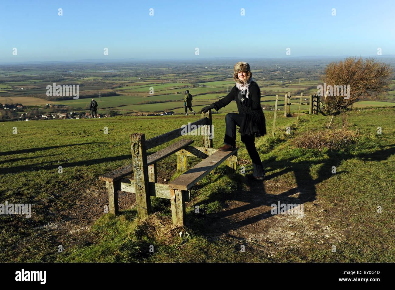 La donna che si arrampica sul cancello mentre si cammina il South Downs Way al Devils Dyke vicino a Brighton SUSSEX REGNO UNITO Foto Stock