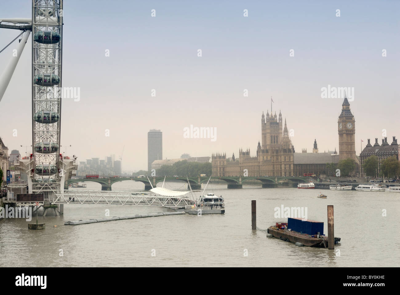 Vista lungo il fiume Tamigi, il London Eye e le case del Parlamento a distanza Foto Stock