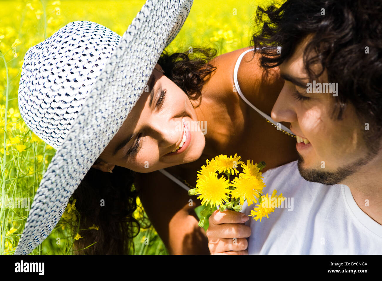 Close-up di donna sorridente che mostra mazzetto di giallo di tarassaco all uomo bello che guarda al suo Foto Stock