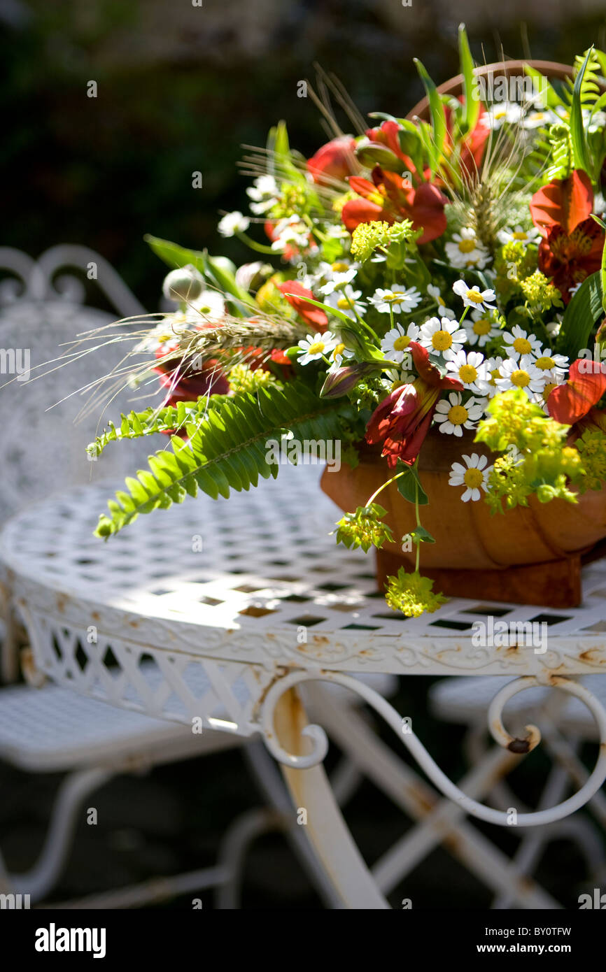 Un cestello di wild estate fiori su un bianco in ferro battuto Tavolo picnic Foto Stock