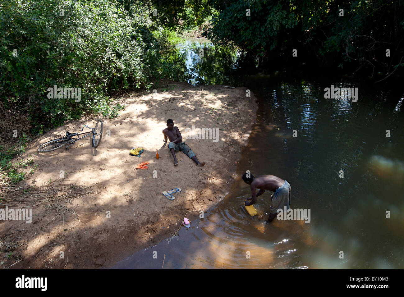 MECEBURI riserva forestale, nei pressi di Nampula, Mozambico, Maggio 2010 : un abitante di un villaggio riempie il contenitore con acqua nel flusso locale. Foto Stock