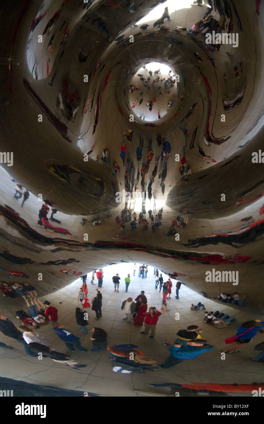 I visitatori guardano la loro riflessione nel Cloud Gate scultura si trova presso l'AT&T Plaza in Millennium Park di Chicago, Illinois. Foto Stock