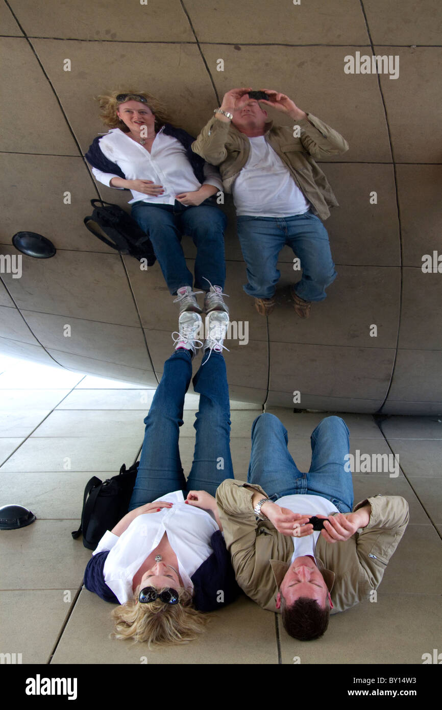 I visitatori guardano la loro riflessione nel Cloud Gate scultura si trova presso l'AT&T Plaza in Millennium Park di Chicago, Illinois. Foto Stock