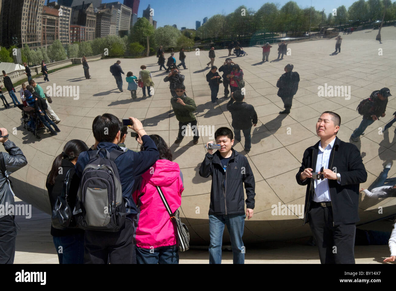 I visitatori guardano la loro riflessione nel Cloud Gate scultura si trova presso l'AT&T Plaza in Millennium Park di Chicago, Illinois. Foto Stock