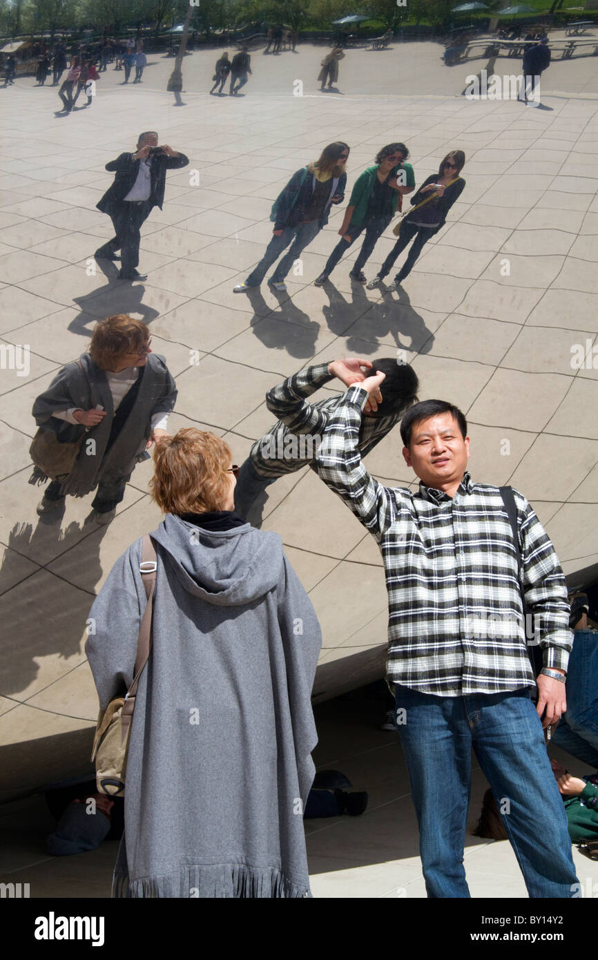 I visitatori guardano la loro riflessione nel Cloud Gate scultura si trova presso l'AT&T Plaza in Millennium Park di Chicago, Illinois. Foto Stock