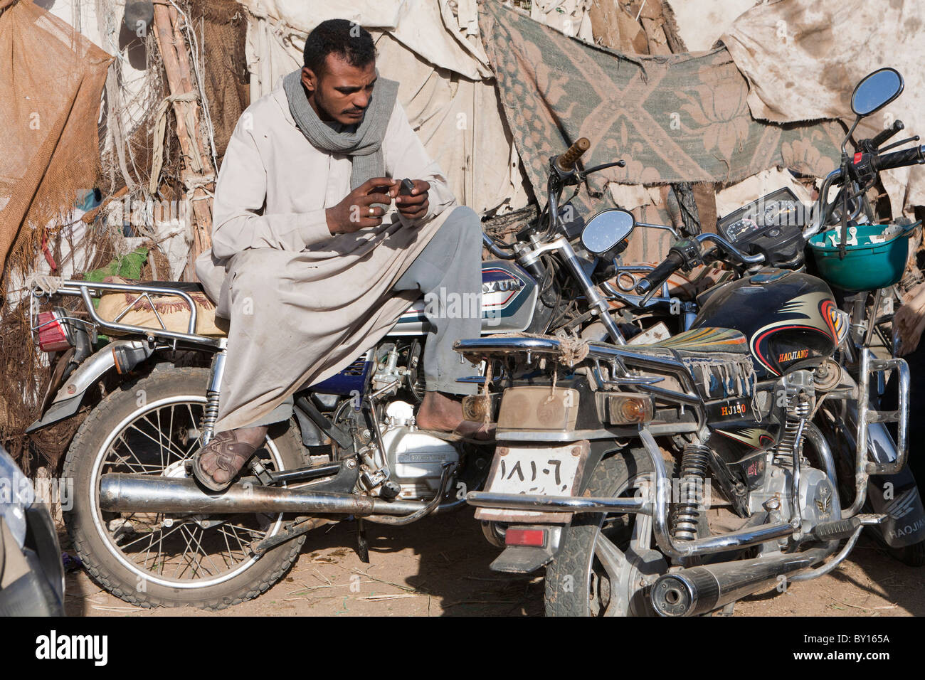 Egyptian uomo seduto sulla moto in settimanalmente il cammello e il mercato del bestiame nei pressi di Luxor, Egitto Foto Stock